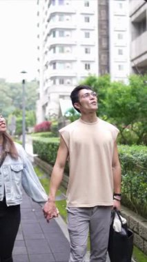 Taipei 'nin Xinyi İlçesi sokaklarında yirmili yaşlarda genç bir Tayvanlı çiftin bahar öğleden sonra yürüdüğü dikey ağır çekim bir video. Adam kolsuz bir bluz giyiyor.