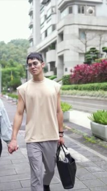 Taipei 'nin Xinyi İlçesi sokaklarında yirmili yaşlarda genç bir Tayvanlı çiftin bahar öğleden sonra yürüdüğü dikey ağır çekim bir video. Adam kolsuz bir bluz giyiyor.
