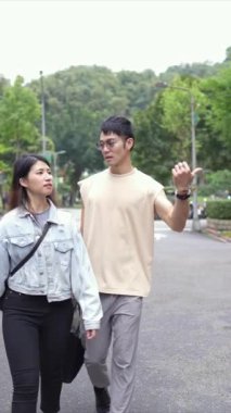 Taipei 'nin Xinyi İlçesi sokaklarında yirmili yaşlarda genç bir Tayvanlı çiftin bahar öğleden sonra yürüdüğü dikey ağır çekim bir video. Adam kolsuz bir bluz giyiyor.