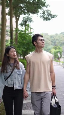 Taipei 'nin Xinyi İlçesi sokaklarında yirmili yaşlarda genç bir Tayvanlı çiftin bahar öğleden sonra yürüdüğü dikey ağır çekim bir video. Adam kolsuz bir bluz giyiyor.