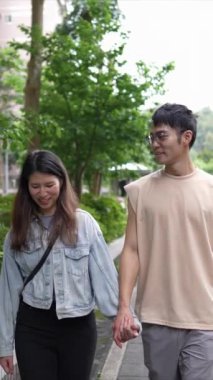Taipei 'nin Xinyi İlçesi sokaklarında yirmili yaşlarda genç bir Tayvanlı çiftin bahar öğleden sonra yürüdüğü dikey ağır çekim bir video. Adam kolsuz bir bluz giyiyor.