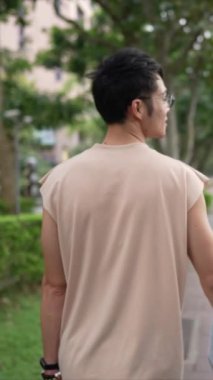 Taipei 'nin Xinyi İlçesi sokaklarında yirmili yaşlarda genç bir Tayvanlı çiftin bahar öğleden sonra yürüdüğü dikey ağır çekim bir video. Adam kolsuz bir bluz giyiyor.