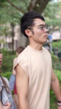 Taipei 'nin Xinyi İlçesi sokaklarında yirmili yaşlarda genç bir Tayvanlı çiftin bahar öğleden sonra yürüdüğü dikey ağır çekim bir video. Adam kolsuz bir bluz giyiyor.