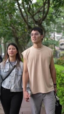 Taipei 'nin Xinyi İlçesi sokaklarında yirmili yaşlarda genç bir Tayvanlı çiftin bahar öğleden sonra yürüdüğü dikey ağır çekim bir video. Adam kolsuz bir bluz giyiyor.