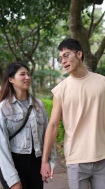 Taipei 'nin Xinyi İlçesi sokaklarında yirmili yaşlarda genç bir Tayvanlı çiftin bahar öğleden sonra yürüdüğü dikey ağır çekim bir video. Adam kolsuz bir bluz giyiyor.