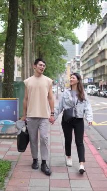 Taipei 'nin Xinyi İlçesi sokaklarında yirmili yaşlarda genç bir Tayvanlı çiftin bahar öğleden sonra yürüdüğü dikey ağır çekim bir video. Adam kolsuz bir bluz giyiyor.