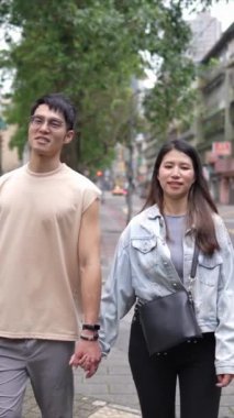 Taipei 'nin Xinyi İlçesi sokaklarında yirmili yaşlarda genç bir Tayvanlı çiftin bahar öğleden sonra yürüdüğü dikey ağır çekim bir video. Adam kolsuz bir bluz giyiyor.