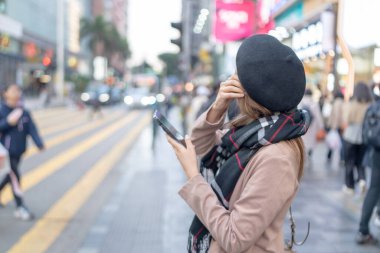 Hong Kong, Batı Kowloon, Tsim Sha Tsui 'de halka açık bir yolda akıllı telefon kullanan 20' li yaşlarda genç bir Hong Kong 'lu kadın. Üzerinde eşarp, bere ve mini etek var..