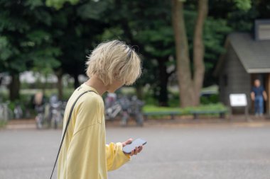 Yazın başlarında, yirmili yaşlarda Japon bir adam, sarı elbiseler giyer, gün boyunca Yoyogi Park, Shibuya, Tokyo 'da dolaşır ve yürür..