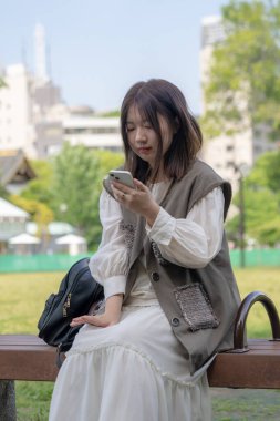 Yazın başlarında, genç bir Çinli değişim öğrencisi Hamamatsucho, Minato, Tokyo yakınlarındaki bir parkta bir bankta oturuyor ve gün içinde akıllı telefon kullanıyor..