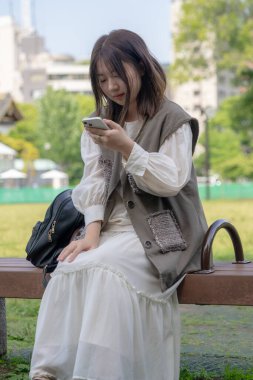 Yazın başlarında, genç bir Çinli değişim öğrencisi Hamamatsucho, Minato, Tokyo yakınlarındaki bir parkta bir bankta oturuyor ve gün içinde akıllı telefon kullanıyor..