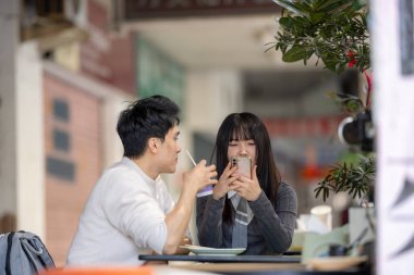 Mart, Zhongshan Anıt Salonu yakınlarındaki Zhongzheng İlçesi, Taipei Şehri, Tayvan, yirmili yaşlarda Tayvanlı bir kadın ve Hong Kong 'lu bir adam yerel dükkanda soya sütü ve turp keki yiyorlar..