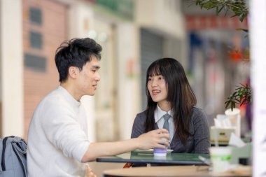 Mart, Zhongshan Anıt Salonu yakınlarındaki Zhongzheng İlçesi, Taipei Şehri, Tayvan, yirmili yaşlarda Tayvanlı bir kadın ve Hong Kong 'lu bir adam yerel dükkanda soya sütü ve turp keki yiyorlar..