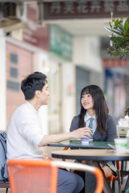 Mart, Zhongshan Anıt Salonu yakınlarındaki Zhongzheng İlçesi, Taipei Şehri, Tayvan, yirmili yaşlarda Tayvanlı bir kadın ve Hong Kong 'lu bir adam yerel dükkanda soya sütü ve turp keki yiyorlar..