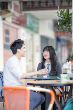 Mart, Zhongshan Anıt Salonu yakınlarındaki Zhongzheng İlçesi, Taipei Şehri, Tayvan, yirmili yaşlarda Tayvanlı bir kadın ve Hong Kong 'lu bir adam yerel dükkanda soya sütü ve turp keki yiyorlar..