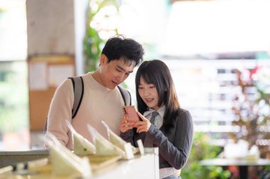 Mart, Zhongshan Anıt Salonu yakınlarındaki Zhongzheng İlçesi, Taipei Şehri, Tayvan, yirmili yaşlarda Tayvanlı bir kadın ve Hong Kong 'lu bir adam yerel dükkanda soya sütü ve turp keki yiyorlar..