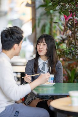 Mart, Zhongshan Anıt Salonu yakınlarındaki Zhongzheng İlçesi, Taipei Şehri, Tayvan, yirmili yaşlarda Tayvanlı bir kadın ve Hong Kong 'lu bir adam yerel dükkanda soya sütü ve turp keki yiyorlar..