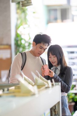 Mart, Zhongshan Anıt Salonu yakınlarındaki Zhongzheng İlçesi, Taipei Şehri, Tayvan, yirmili yaşlarda Tayvanlı bir kadın ve Hong Kong 'lu bir adam yerel dükkanda soya sütü ve turp keki yiyorlar..