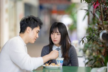 Mart, Zhongshan Anıt Salonu yakınlarındaki Zhongzheng İlçesi, Taipei Şehri, Tayvan, yirmili yaşlarda Tayvanlı bir kadın ve Hong Kong 'lu bir adam yerel dükkanda soya sütü ve turp keki yiyorlar..