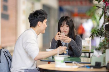 Mart, Zhongshan Anıt Salonu yakınlarındaki Zhongzheng İlçesi, Taipei Şehri, Tayvan, yirmili yaşlarda Tayvanlı bir kadın ve Hong Kong 'lu bir adam yerel dükkanda soya sütü ve turp keki yiyorlar..