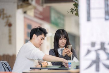 Mart, Zhongshan Anıt Salonu yakınlarındaki Zhongzheng İlçesi, Taipei Şehri, Tayvan, yirmili yaşlarda Tayvanlı bir kadın ve Hong Kong 'lu bir adam yerel dükkanda soya sütü ve turp keki yiyorlar..