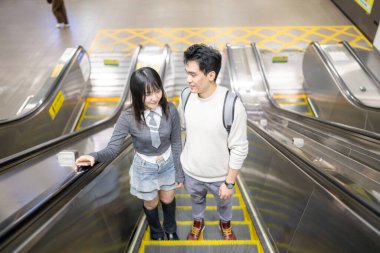 Mart ayında yirmili yaşlarda Tayvanlı bir kadın ve Hong Kong 'lu bir adam Taipei, Tayvan' daki Zhongzheng Bölgesi 'ndeki bir istasyonda yürüyen merdivene biniyorlar..