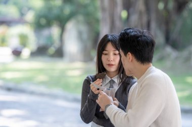 Mart ayında yirmili yaşlarda Tayvanlı bir kadın ve Hong Kong 'lu bir adam Tayvan' ın Taipei şehrindeki Zhongzheng bölgesinde bir parkta mola verip abur cubur yiyip su içiyorlar..