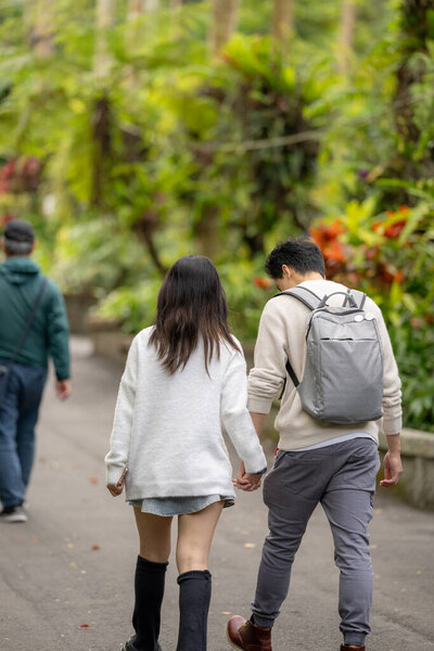 In March, a Taiwanese woman in her twenties and a Hong Kong man are walking in a lush botanical garden in Zhongzheng District, Taipei City, Taiwan.