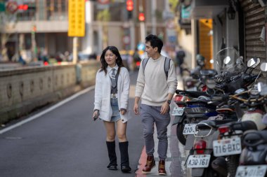 Tayvanlı genç bir kadın ve Hong Kong 'lu genç bir adam, Mart ayında birçok park etmiş scooterıyla birlikte Zhongshan Memorial Hall İstasyonu yakınlarında yürüyorlar..