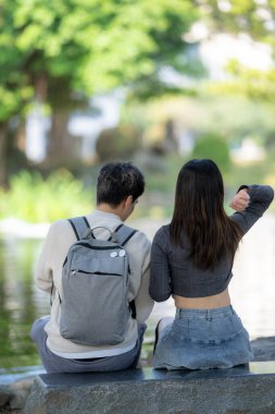Mart ayında, Tayvanlı bir kadın ve Hong Kong 'lu bir adam Tayvan' ın Taipei şehrindeki Zhongzheng bölgesinde bir parkta koi balığı besliyor..