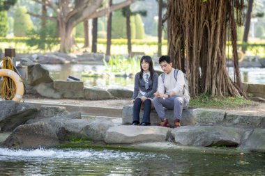Mart ayında, Tayvanlı bir kadın ve Hong Kong 'lu bir adam Tayvan' ın Taipei şehrindeki Zhongzheng bölgesinde bir parkta koi balığı besliyor..