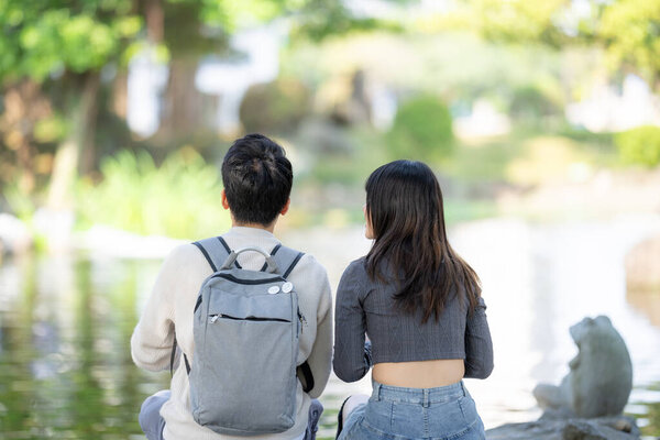 In March, a Taiwanese woman in her twenties and a Hong Kong man are feeding koi fish in a park in Zhongzheng District, Taipei City, Taiwan.