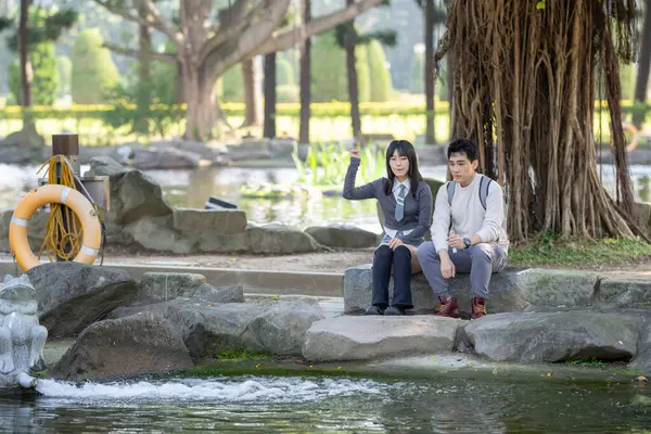 stock image In March, a Taiwanese woman in her twenties and a Hong Kong man are feeding koi fish in a park in Zhongzheng District, Taipei City, Taiwan.