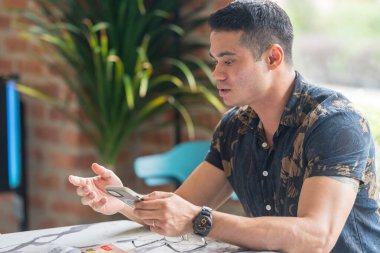 Otuz yaşlarında Hintli bir Malezyalı adam, Malezya 'nın Selangor kentindeki şık bir kafede akıllı telefonuyla vakit geçiriyor..