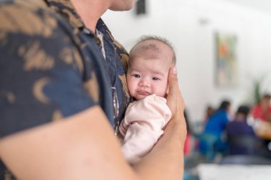 Otuz yaşlarında Hintli bir Malezyalı birkaç aylık bebeği güneşli bir yaz öğleden sonrasında Selangor, Malezya 'da şık bir kafede tutuyor..