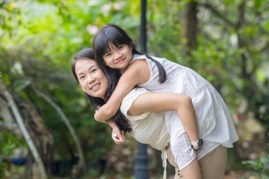 20 'li yaşlarda Çinli bir Malezyalı kadın ve altı yaşında bir kız güneşli bir yaz öğleden sonrasında Selangor, Malezya' da şık bir kafede yeşillikler ve çiçekler arasında vakit geçiriyorlar..
