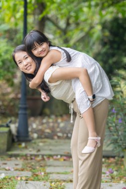20 'li yaşlarda Çinli bir Malezyalı kadın ve altı yaşında bir kız güneşli bir yaz öğleden sonrasında Selangor, Malezya' da şık bir kafede yeşillikler ve çiçekler arasında vakit geçiriyorlar..