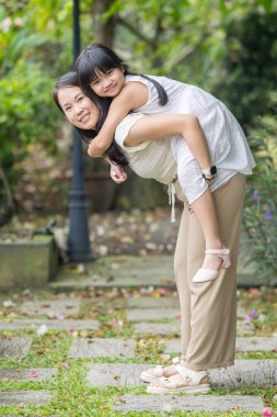 20 'li yaşlarda Çinli bir Malezyalı kadın ve altı yaşında bir kız güneşli bir yaz öğleden sonrasında Selangor, Malezya' da şık bir kafede yeşillikler ve çiçekler arasında vakit geçiriyorlar..