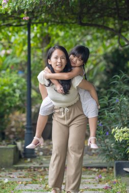 20 'li yaşlarda Çinli bir Malezyalı kadın ve altı yaşında bir kız güneşli bir yaz öğleden sonrasında Selangor, Malezya' da şık bir kafede yeşillikler ve çiçekler arasında vakit geçiriyorlar..