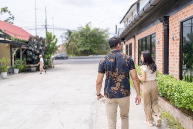 20 'li yaşlarda Çinli bir Malezyalı kadın ve Hintli bir Malezyalı erkek yazın Selangor, Malezya' da şık bir kafede yeşillikler ve çiçekler arasında vakit geçiriyorlar..