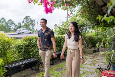 20 'li yaşlarda Çinli bir Malezyalı kadın ve Hintli bir Malezyalı erkek yazın Selangor, Malezya' da şık bir kafede yeşillikler ve çiçekler arasında vakit geçiriyorlar..