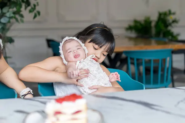 stock image A Malaysian girl holding a few-months-old baby at a stylish cafe in Selangor, Malaysia, on an early summer afternoon.