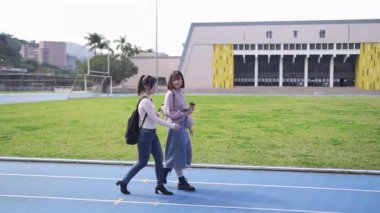 Tayvan 'ın Taipei şehrinde Wenshan Bölgesi' nde bir üniversite kampüsünde yirmili yaşlarının başında yürüyen ve dostça sohbet eden iki genç Tayvanlı kadının yavaş çekim videosu..