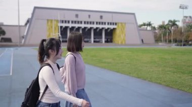 Tayvan 'ın Taipei şehrinde Wenshan Bölgesi' nde bir üniversite kampüsünde yirmili yaşlarının başında yürüyen ve dostça sohbet eden iki genç Tayvanlı kadının yavaş çekim videosu..
