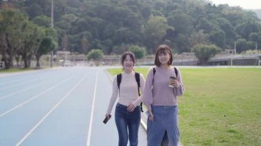 Tayvan 'ın Taipei şehrinde Wenshan Bölgesi' nde bir üniversite kampüsünde yirmili yaşlarının başında yürüyen ve dostça sohbet eden iki genç Tayvanlı kadının yavaş çekim videosu..