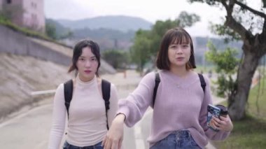 Tayvan 'ın Taipei şehrinde Wenshan Bölgesi' nde bir üniversite kampüsünde yirmili yaşlarının başında yürüyen ve dostça sohbet eden iki genç Tayvanlı kadının yavaş çekim videosu..