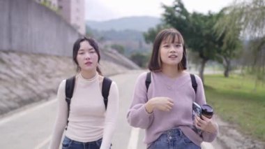 Tayvan 'ın Taipei şehrinde Wenshan Bölgesi' nde bir üniversite kampüsünde yirmili yaşlarının başında yürüyen ve dostça sohbet eden iki genç Tayvanlı kadının yavaş çekim videosu..