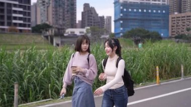 Tayvan 'ın Taipei şehrinde Wenshan Bölgesi' nde bir üniversite kampüsünde yirmili yaşlarının başında yürüyen ve dostça sohbet eden iki genç Tayvanlı kadının yavaş çekim videosu..