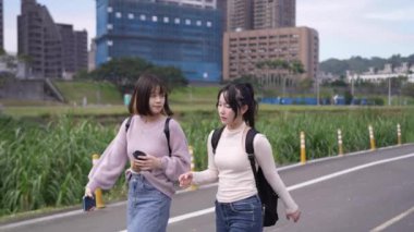 Tayvan 'ın Taipei şehrinde Wenshan Bölgesi' nde bir üniversite kampüsünde yirmili yaşlarının başında yürüyen ve dostça sohbet eden iki genç Tayvanlı kadının yavaş çekim videosu..