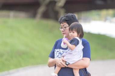 Malezya 'daki Kuala Lumpur Şehir Merkezi' ndeki KLCC Parkı 'nda 30' lu yaşlardaki babasıyla çocuk parkı ekipmanlarında oynayan bir Çinli kız..